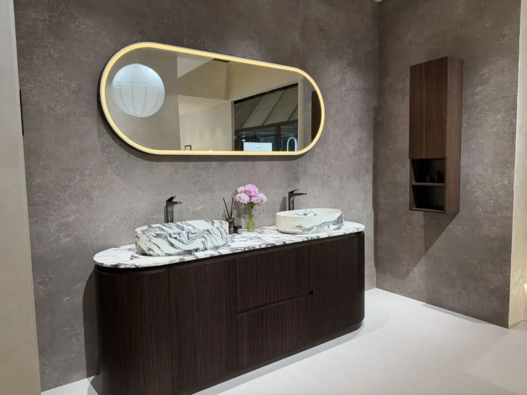 Modern bathroom vanity with wood-grain cabinet, white countertop sink, and round mirror at 2026 Shanghai KBC Expo